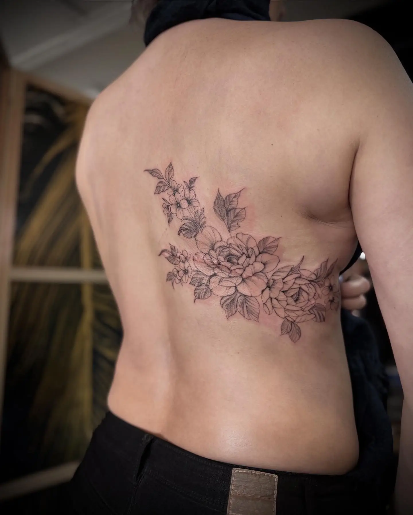 Tatouage fleur minimaliste trait fin noir sur côtes femme par Cartis.Ink tatoueuse Fineline Encre Et Mer Port-Fréjus