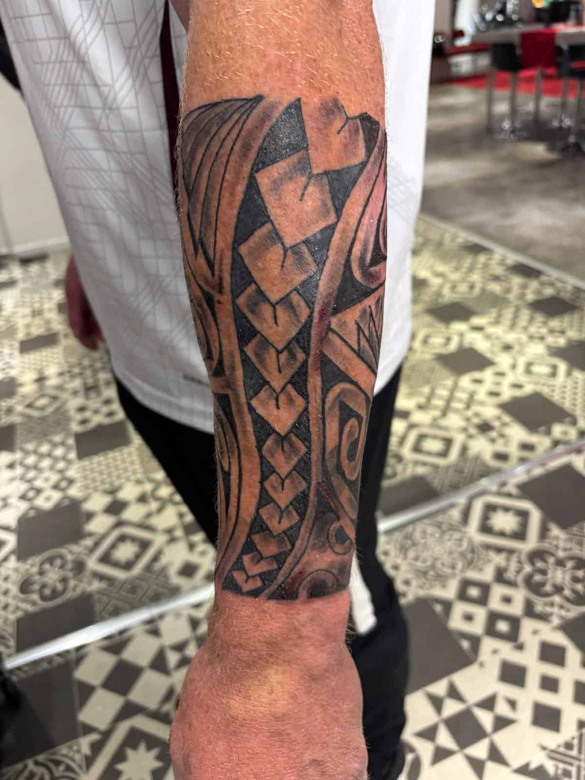 Tatouage tribal Maori polynésien motifs traditionnels noir sur bras par Fred Tattoo spécialiste Maori Encre Et Mer Fréjus